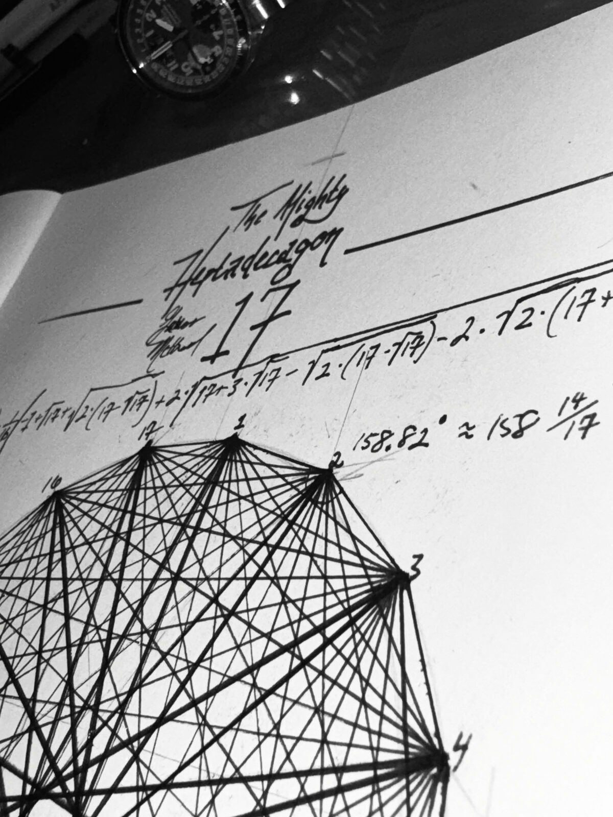 The finished heptadecagon in black and white, photographed at an angle beneath a wristwatch