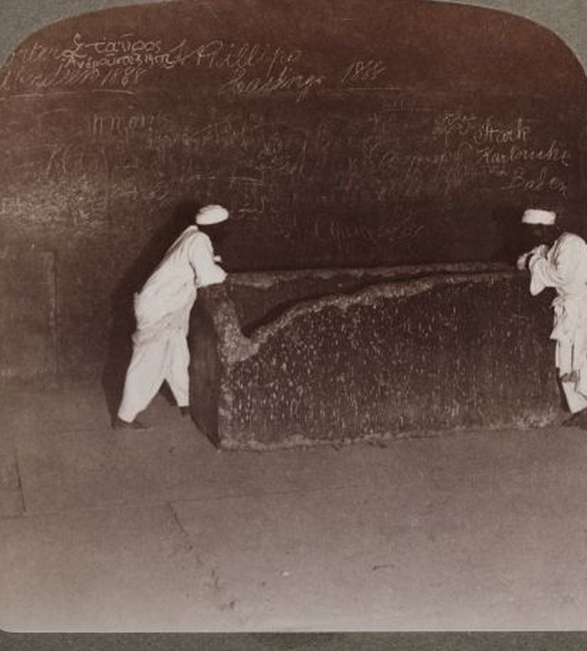 Two men lean on the granite box in the King's Chamber in a 1904 stereograph; the broken corner faces the camera
